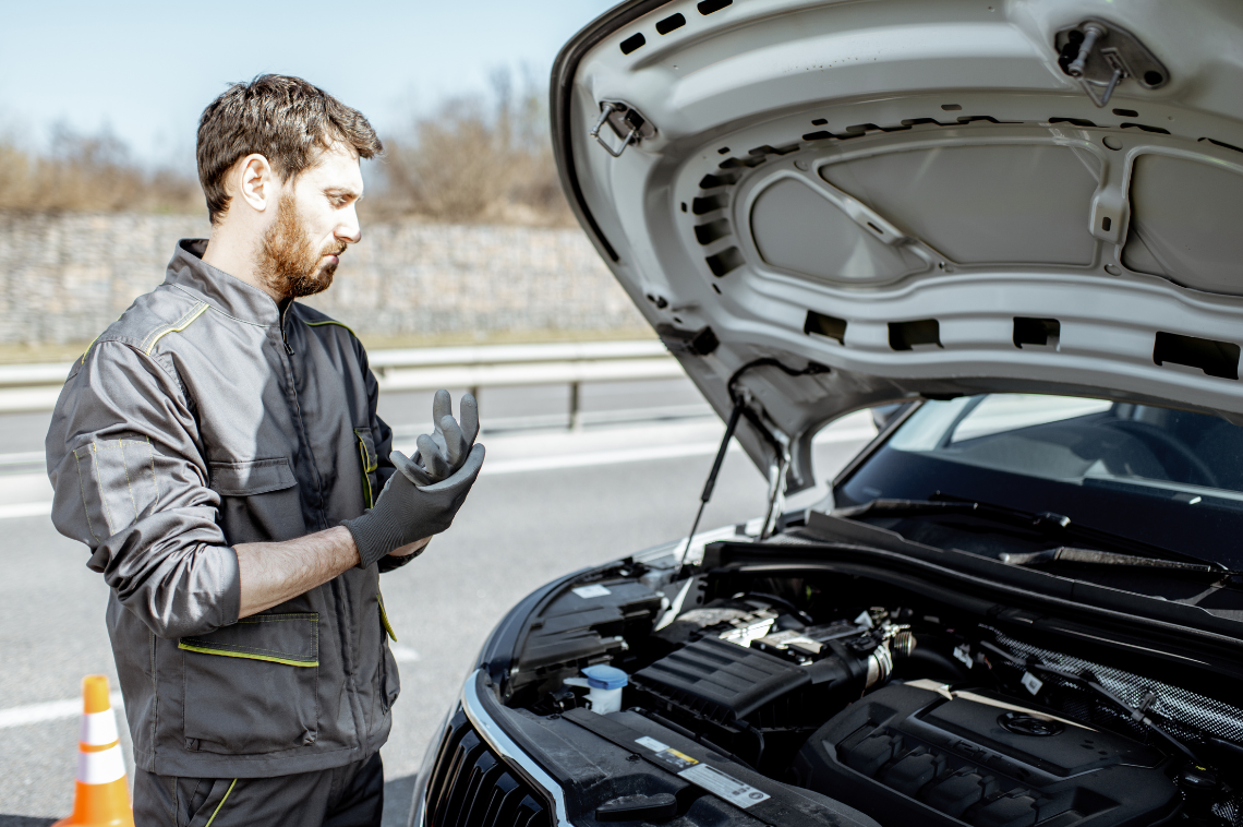 A mobile mechanic in Liverpool adjusts his glove as he is about to fix a car's engine. The car has its bonnet raised.