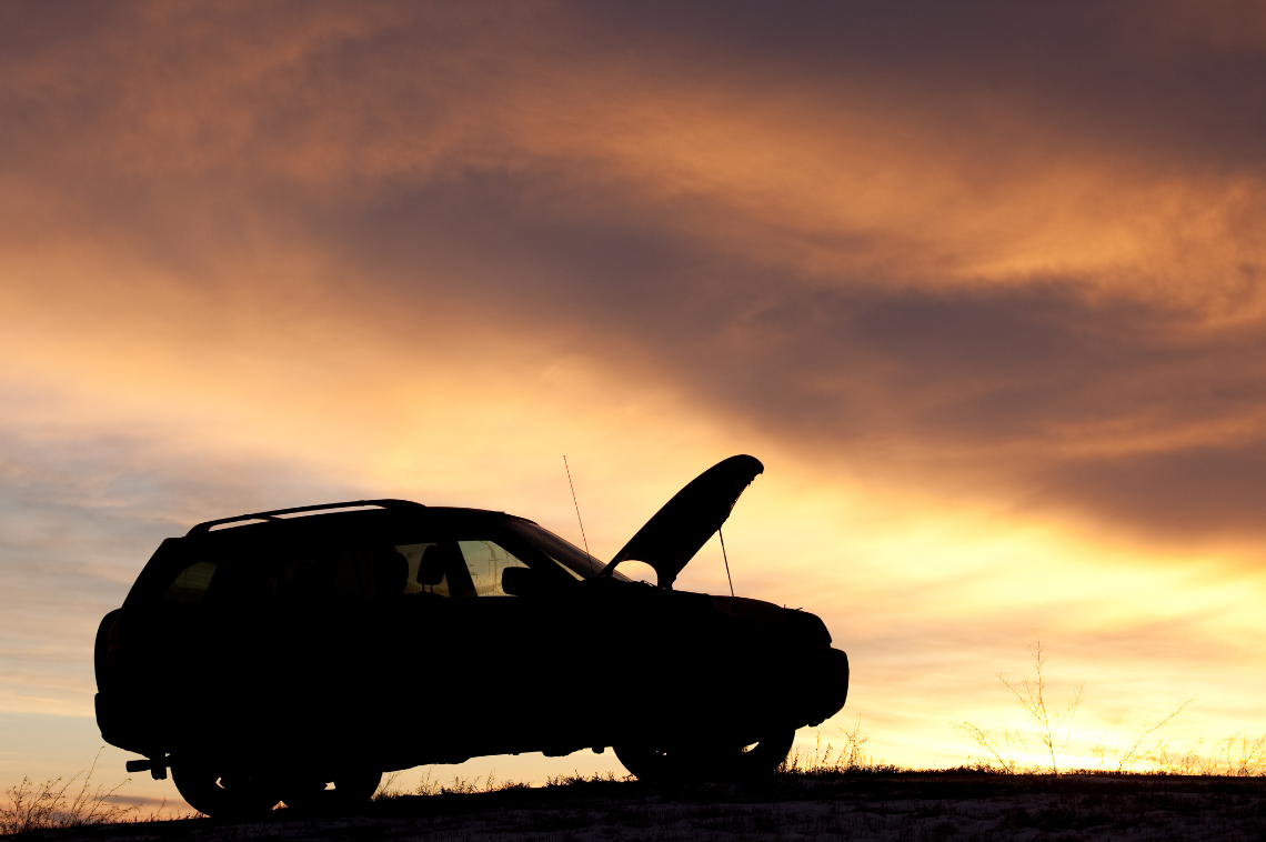 A car stranded on its own with its bonnet raised on a summer's evening.