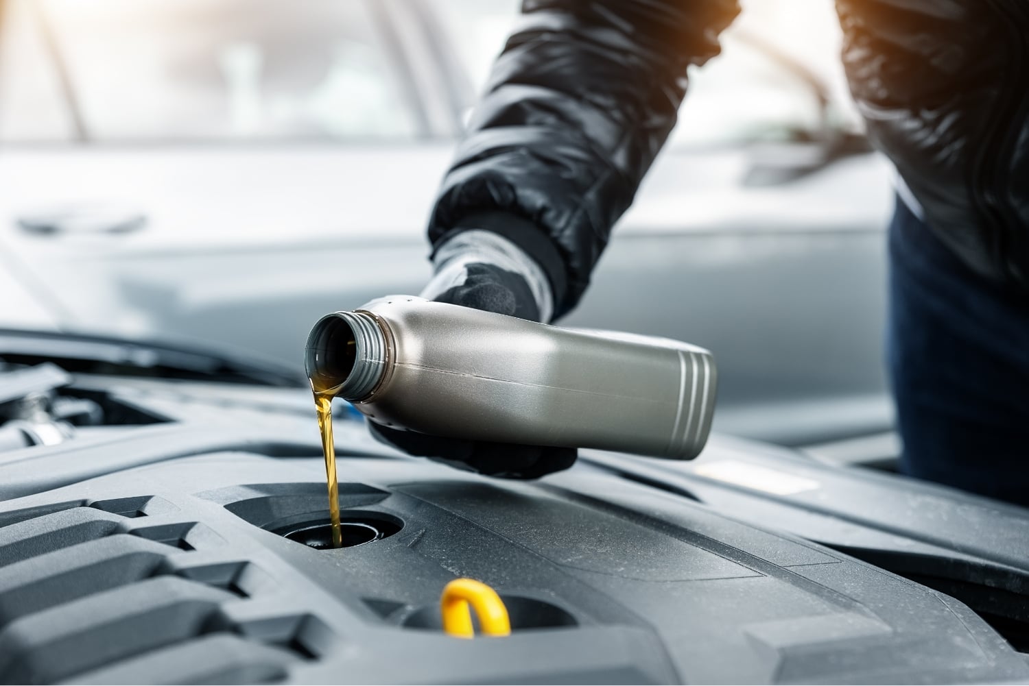 A mechanic pours oil into an engine.